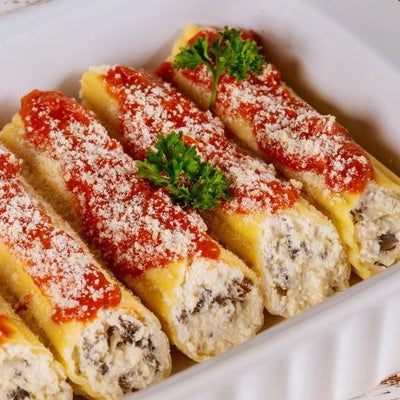 White dish with sauced ricotta and spinach cannelloni