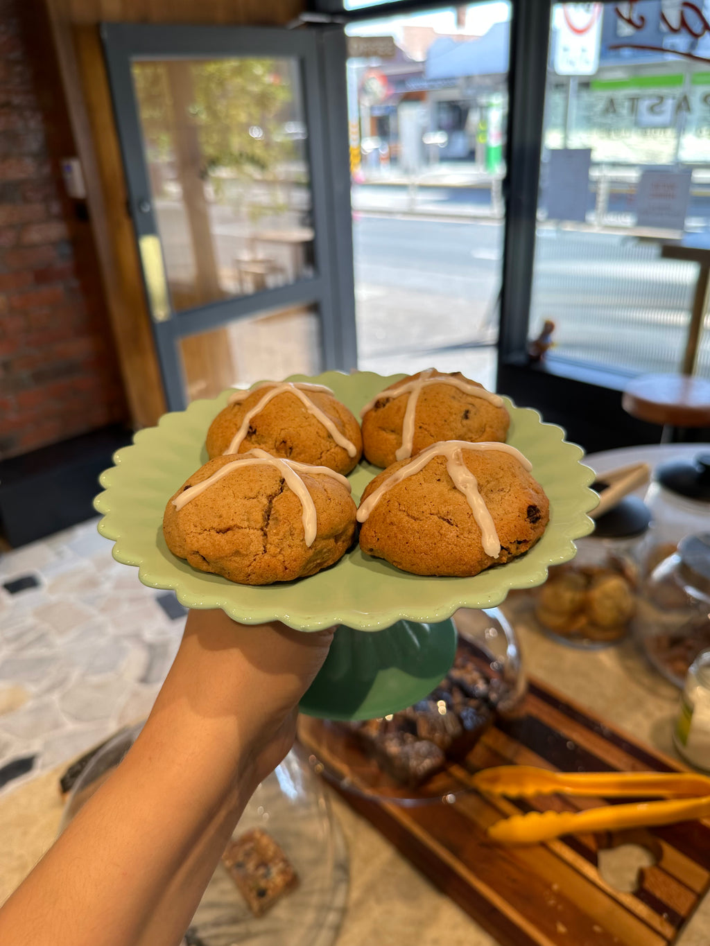 Green plate of hot cross bun cookies fresh in the storefront