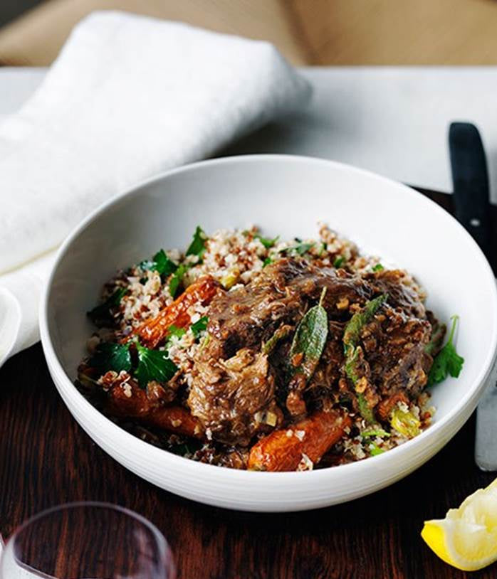 Plated lamb cous cous with glass of red wine and lemon garnish