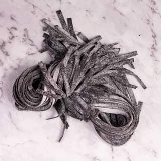 Handrolled black squid ink pasta on marbled bench