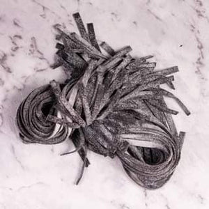 Handrolled black squid ink pasta on marbled bench